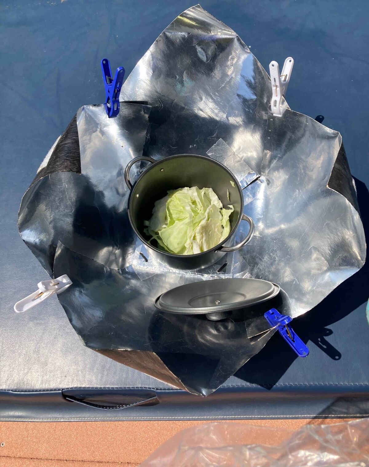 A member-built solar cooker cooking cabbage